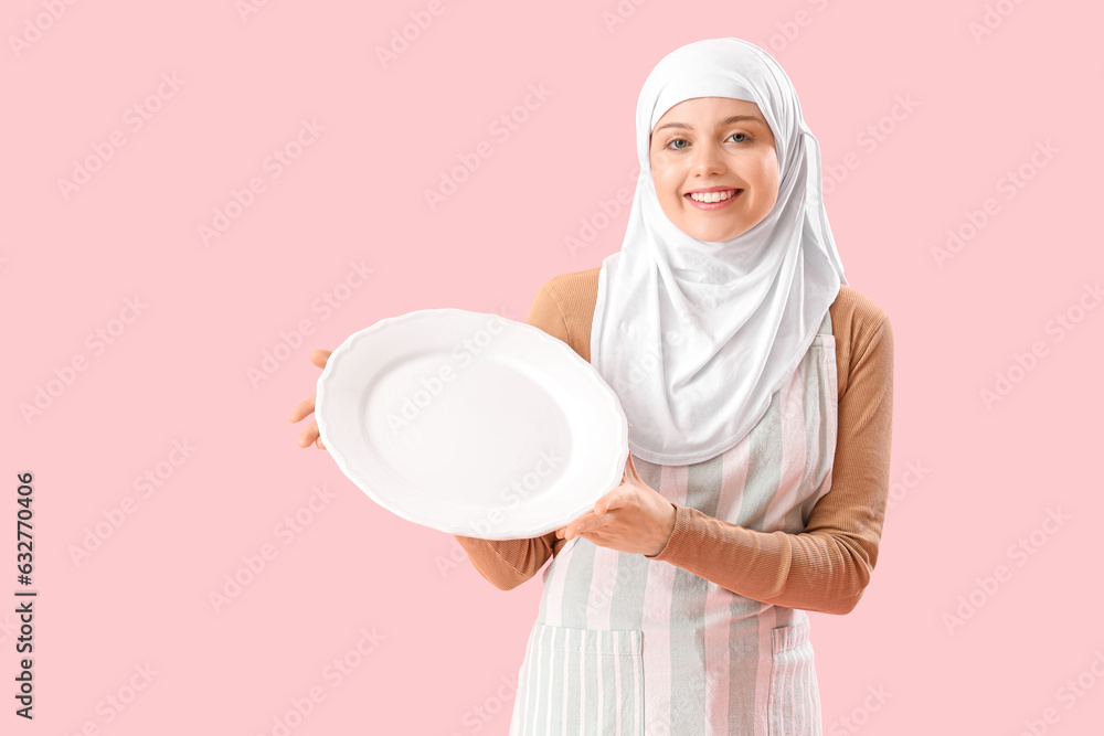 Beautiful Arabian woman with empty plate on pink background Beautiful Arabian woman with empty plate on pink background