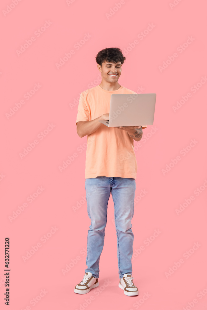 Male programmer working with computer on pink background Male programmer working with computer on pink background