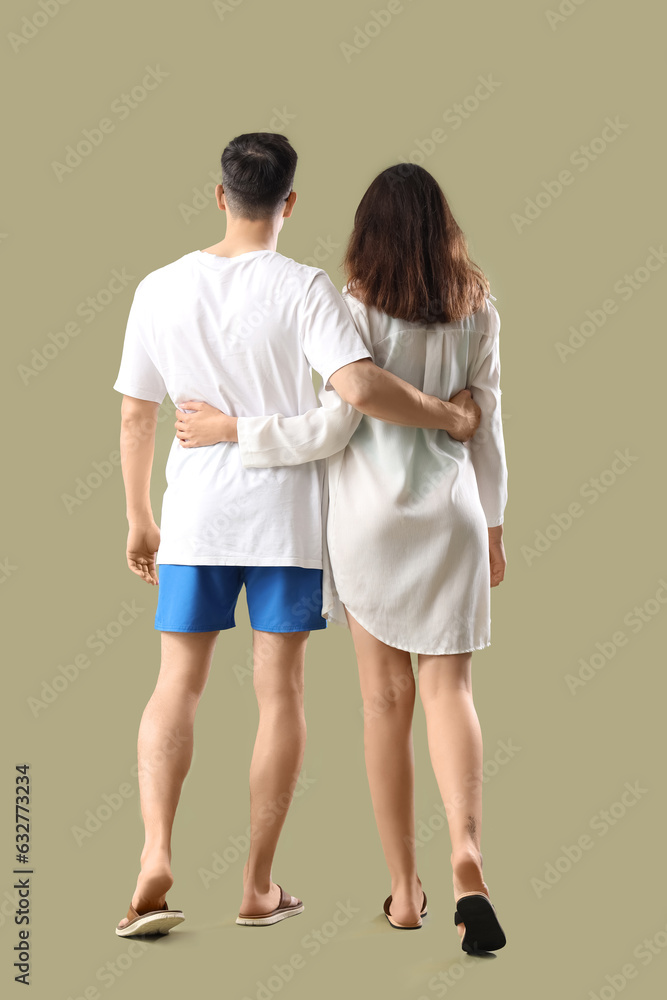 Young couple in summer clothes on green background, back view Young couple in summer clothes on green background, back view