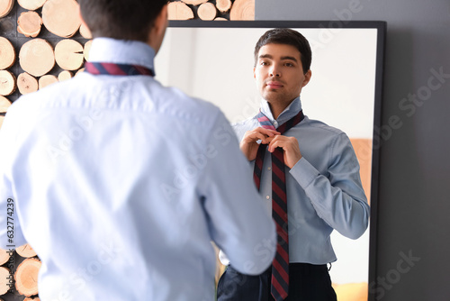 Young businessman tying his...