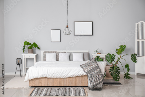 Interior of modern bedroom with comfortable double bed  white pillows and houseplants