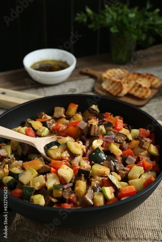 Delicious ratatouille and spoon in baking dish on table