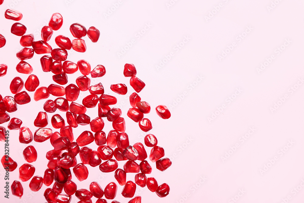 Flying fresh pomegranate seeds on pink background