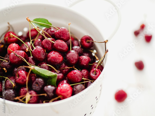 Fresh cherries in white colander.