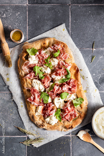 Pizza with prosciutto, cheese and arugula