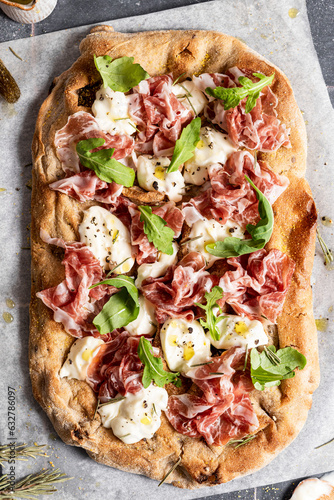 Pizza with prosciutto, cheese and rocket leaves