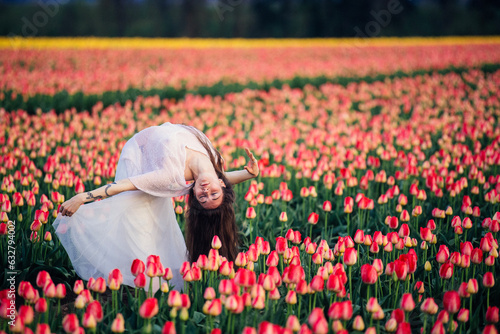 Woman in white dress, doing a back bend, in field of tulips