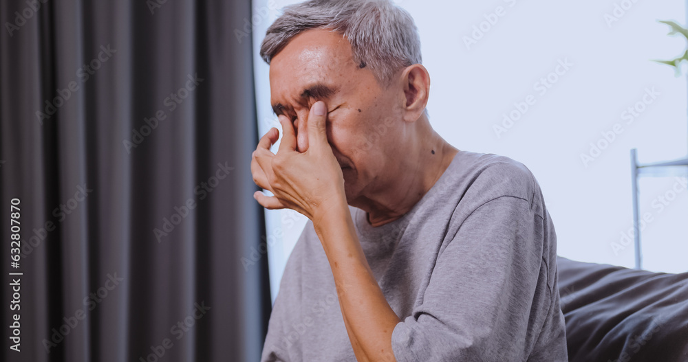 Fototapeta premium An elderly Asian man has blurred vision from staring at his phone for a long time.