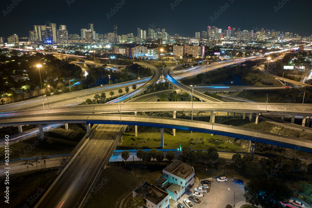Aerial view of american highway junction at night with fast driving vehicles in Miami, Florida. View from above of USA transportation infrastructure