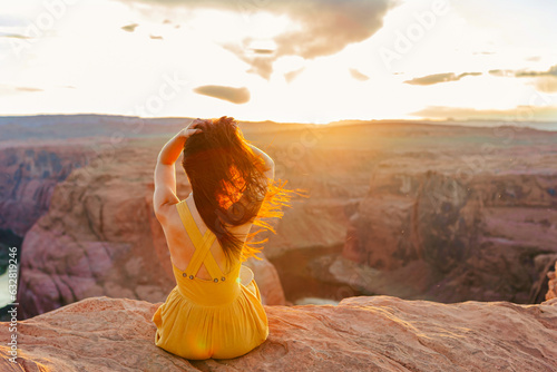 Beautiful woman in yellow dress on the edge of the cliff at Horseshoe Band Canyon in Paje, Arizona. Beautiful nature in USA