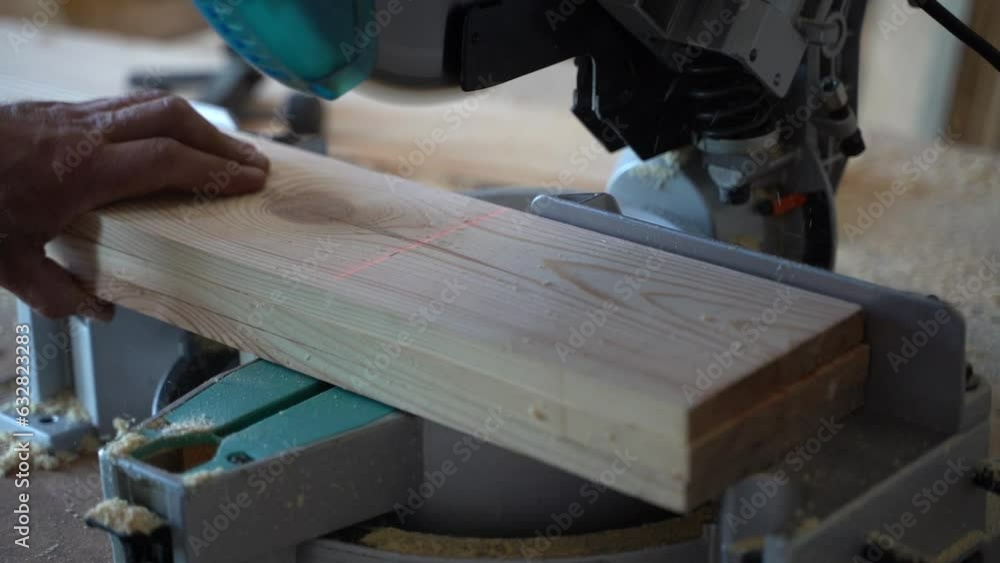 Pine boards are trimmed with a miter saw, close-up Pine boards are trimmed with a miter saw, close-up