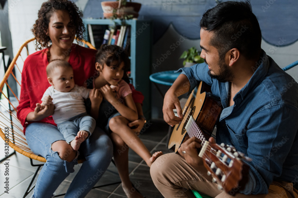 Φωτογραφία latin father playing guitar, singing and having fun with his family wife baby an