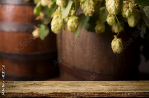 mug of beer, wheat ears, green hops and beer barrel on a wooden background
