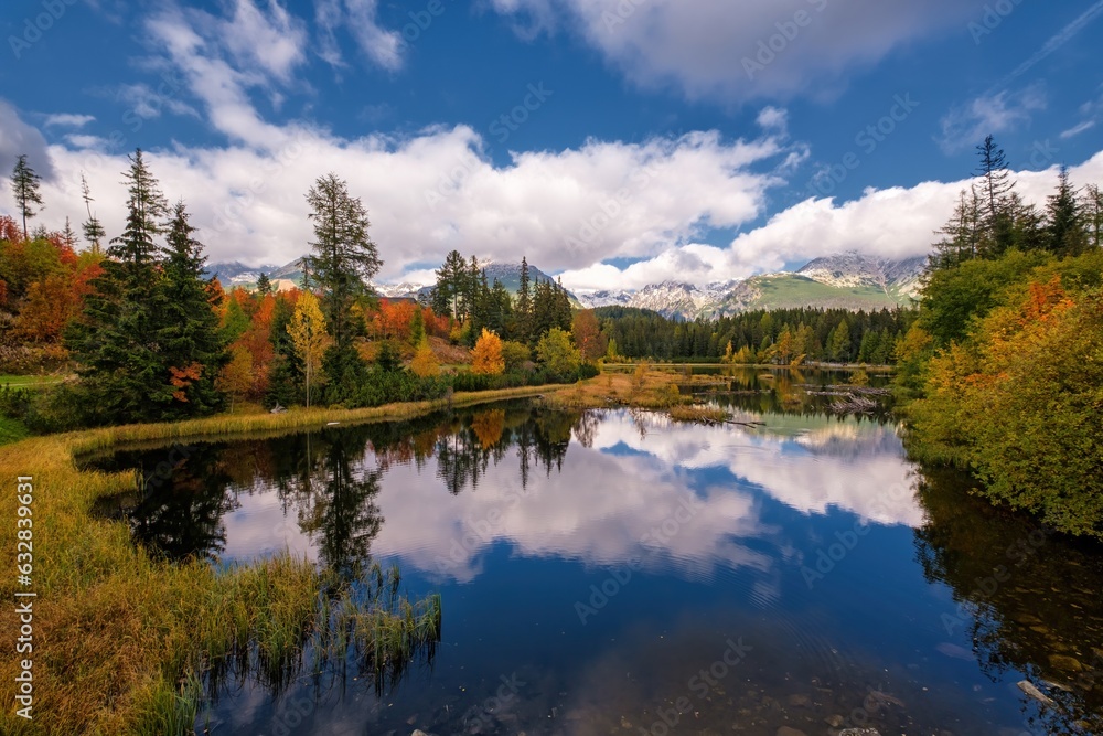 Beautiful mountain lake with a reflection of autum park on water and high peaks in the Background. The new Strbske pleso lake in High Tatras mountains in Slovakia.