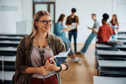 Happy female college student in lecture hall looking away.