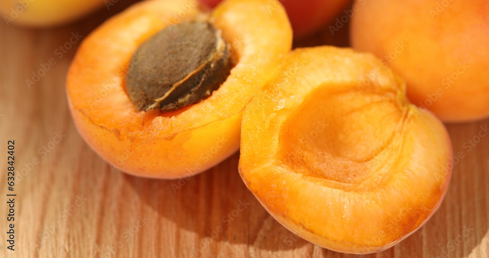 Apricot halves on a wooden table. Fresh fruits on a sunny day. Vegetarian food. Summer harvest. High quality photo. Apricot halves on a wooden table. Fresh fruits on a sunny day. Vegetarian food. Summer harvest. High quality photo.
