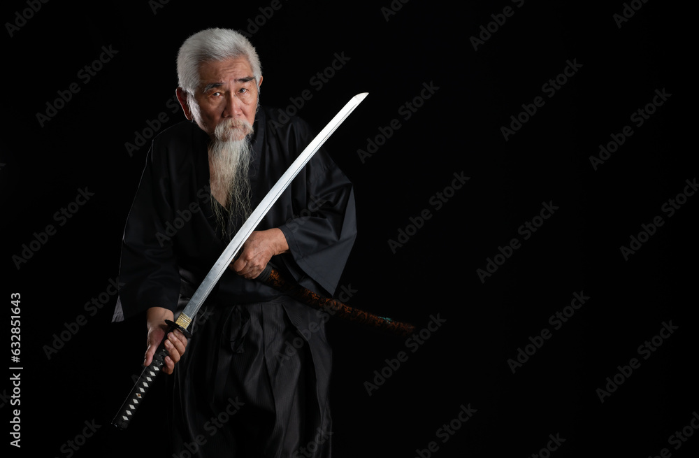 Senior Japanese samurai with katana sword on black background, studio shot