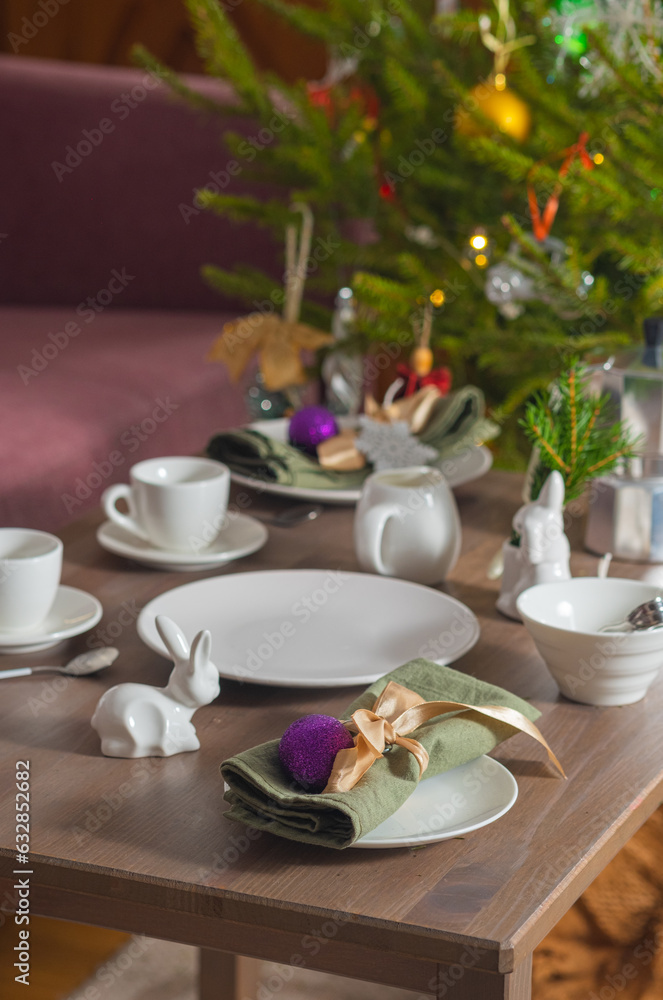 Coffee serving with white tableware for Christmas on a table near a dark pink sofa. Christmas concept, table setting Coffee serving with white tableware for Christmas on a table near a dark pink sofa. Christmas concept, table setting
