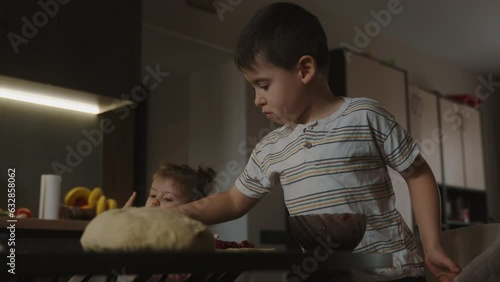 Boy sitting with his sister at the kitchen table, the dough already being prepared to start baking the pies