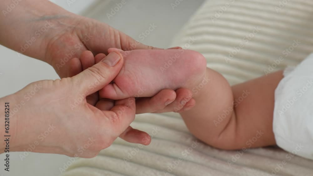 Close-up hands of unrecognizable mother or masseuse massaging foot of infant baby. Little infant receiving feet reflexology at home. Concept of prophylaxis, relaxation and healthy development. Close-up hands of unrecognizable mother or masseuse massaging foot of infant baby. Little infant receiving feet reflexology at home. Concept of prophylaxis, relaxation and healthy development.