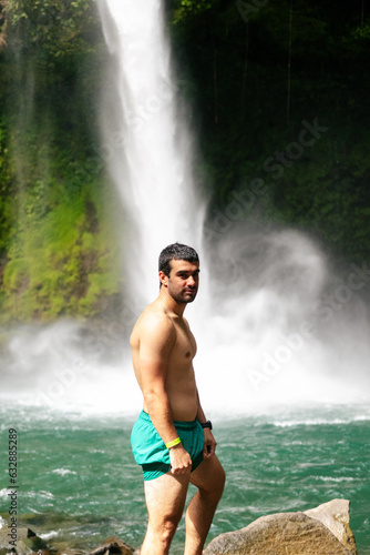Young man standing in front of a waterfall