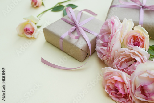 Concept background with light pink roses and wrapped kraft gift box on beige background. Flower card. Holiday, congratulations, happy mothers day. International Women's day. Side view. © Photo