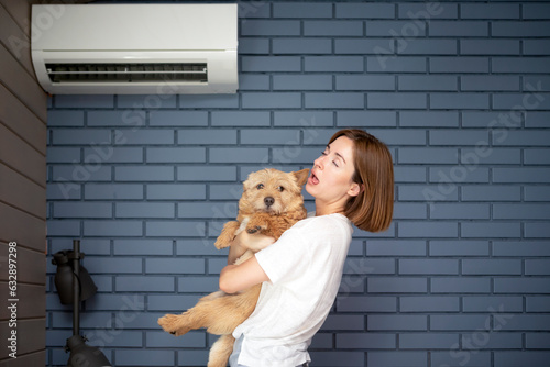 Young woman and her cute dog suffering from extreme heat, record breaking summer heat, trying to keep cool and well air at home