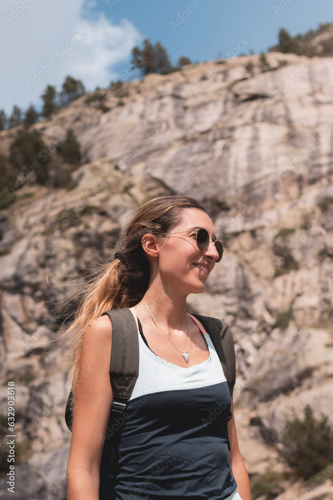 Young woman with sunglasses smiling on the mountain during her hiking and adventure route Young woman with sunglasses smiling on the mountain during her hiking and adventure route