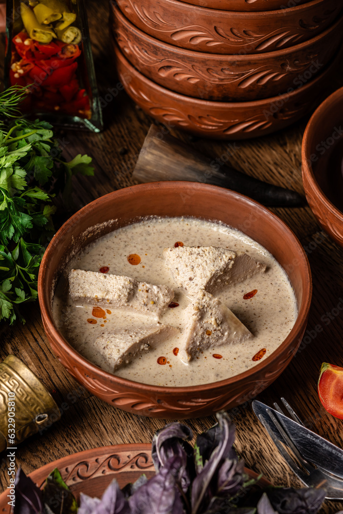 Georgian cuisine. Chicken fillet in a creamy sauce with Georgian spices, in a clay plate in a restaurant. Georgian cuisine. Chicken fillet in a creamy sauce with Georgian spices, in a clay plate in a restaurant.