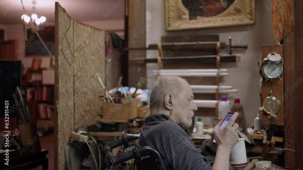 An old craftsman in a wheelchair rests in his workshop