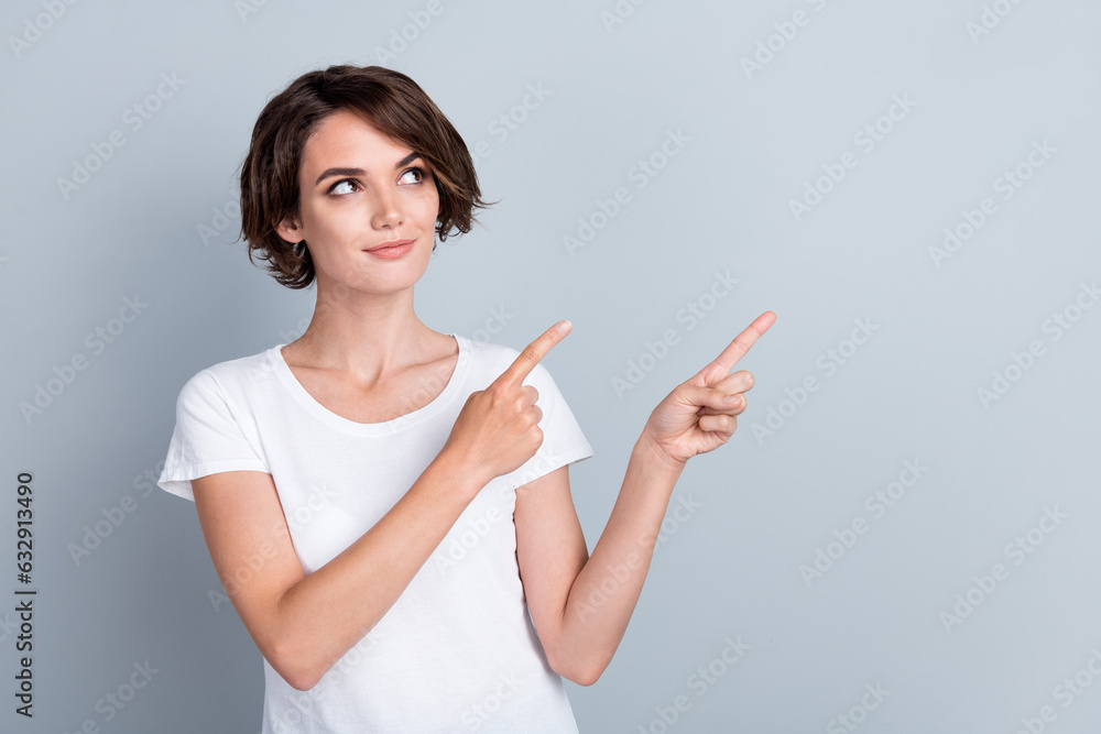 Photo of pretty thoughtful woman dressed white t-shirt pointing two fingers looking empty space isolated grey color background