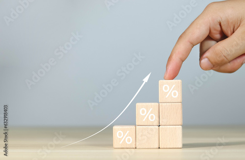 Financial interest rate holding wooden block with percentage sign and up arrow, financial growth, interest rate increase, inflation rate, selling price and tax hike concept and rate simulation 