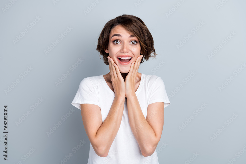 Photo of funky excited woman dressed white t-shirt arms cheeks open mouth isolated grey color background Photo of funky excited woman dressed white t-shirt arms cheeks open mouth isolated grey color background