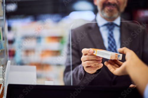 A smiling man dressed in a suit, buying a medical product in a pharmacy.