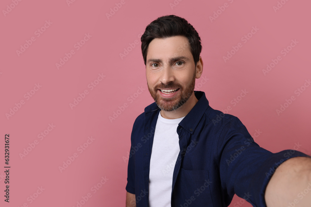 Smiling man taking selfie on pink background, space for text Smiling man taking selfie on pink background, space for text