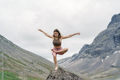 The trainer is engaged in pilates asana and stretching a slim body. Young woman yoga workout. Asana pose harmony with nature mountain background, Meditation and mental health of a person. 