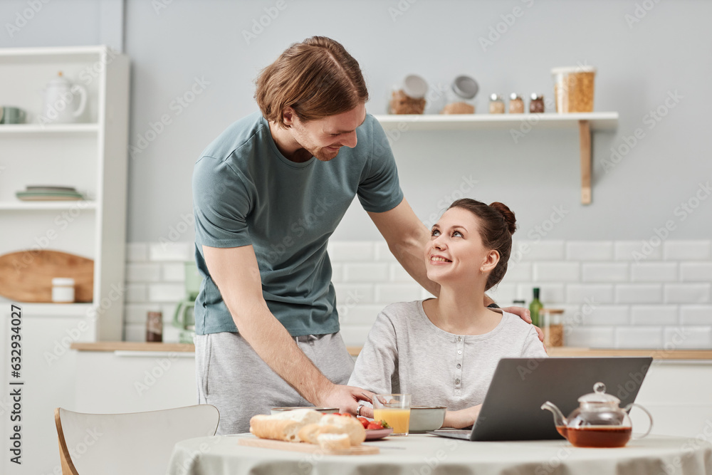 Portrait of affectionate young couple enjoying breakfast in morning together and looking at each other