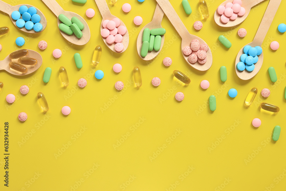 Vitamins of different colors in wooden spoons on a yellow background. Top view of scattered bright pills. Pharmaceutical industry. Health care and medicine. Pharmacy product. Copy space Vitamins of different colors in wooden spoons on a yellow background. Top view of scattered bright pills. Pharmaceutical industry. Health care and medicine. Pharmacy product. Copy space