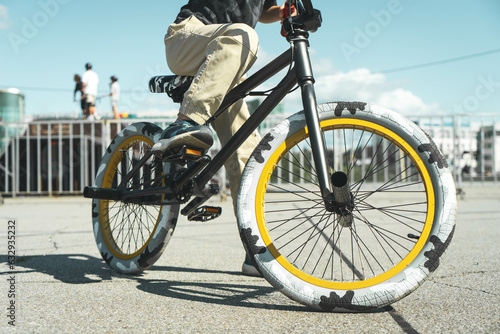 A boy in a cap and T-shirt rides a bmx bike and learns to perform tricks near a special ramp for stunts Fototapet