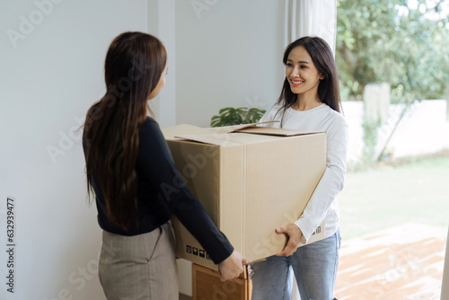 Young woman couple smiling happy and moving box together at new home. Homosexual-LGBTQ concept