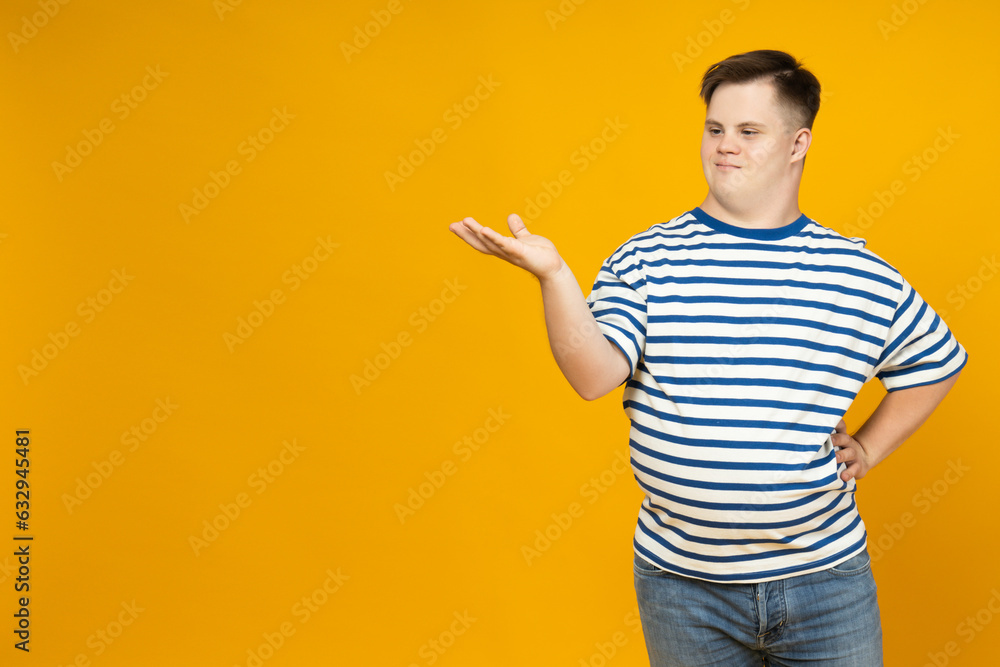 Smiling young man with down syndrome posing on orange background, place for text Smiling young man with down syndrome posing on orange background, place for text