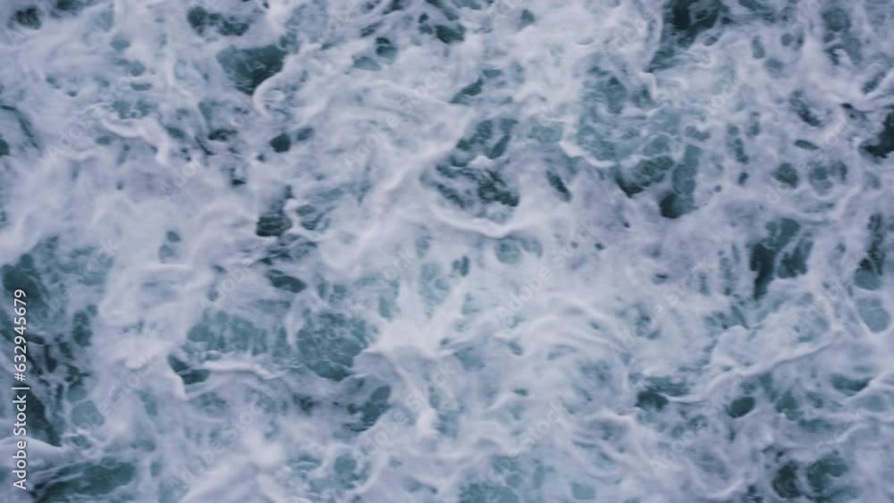 Slow motion top-down shot of waves crashing along the beach creating patterns Slow motion top-down shot of waves crashing along the beach creating patterns