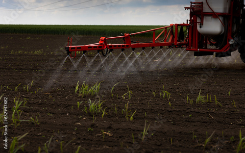 a red tractor spraying the ground with pesticides