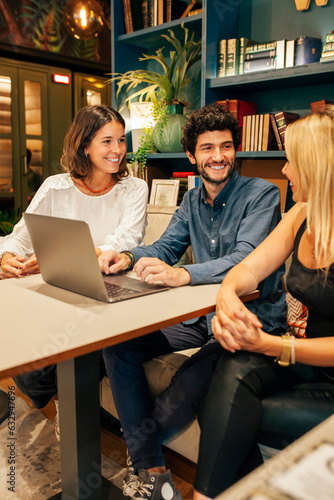 Group of focused young multiracial colleagues gathering around table with laptop and discussing startup strategy while having meeting in modern coworking space.
