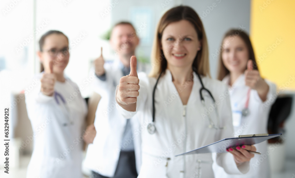 Successful medical team in white coats hold their thumbs up. Medical services concept