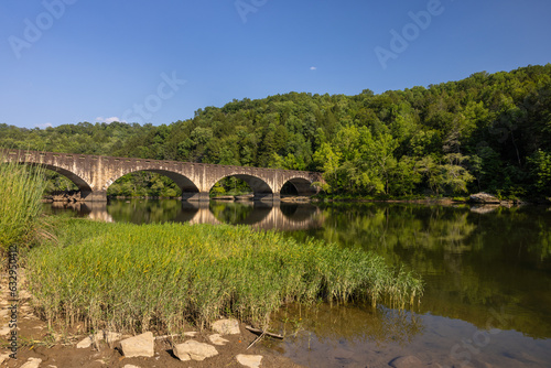 A bridge with arches crossing a calm river during summer. photo