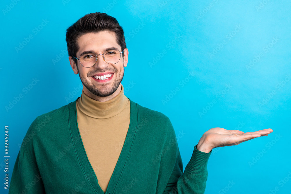 Photo of nice cheerful person beaming smile arm palm hold demonstrate empty space ad isolated on blue color background Photo of nice cheerful person beaming smile arm palm hold demonstrate empty space ad isolated on blue color background