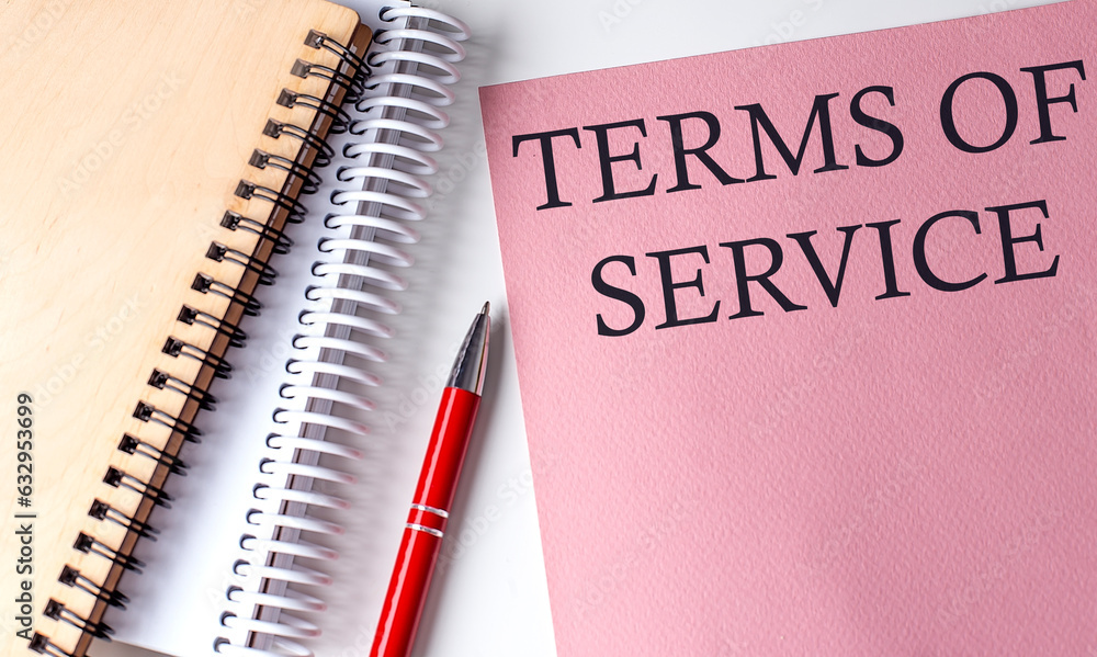 TERMS OF SERVICE word on the pink paper with office tools on white background TERMS OF SERVICE word on the pink paper with office tools on white background