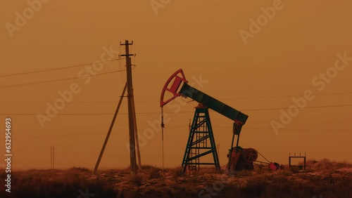Pumping petroleum Rig in desert at sunset. Oil industry. Pump Jack Extracting Crude Oil from a Oil Well. Fossil Fuel Energy. Working oil pump jacks. slow motion video photo