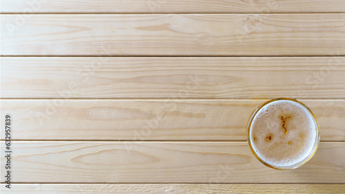 Light beer in glass on wooden background with copy space, top view